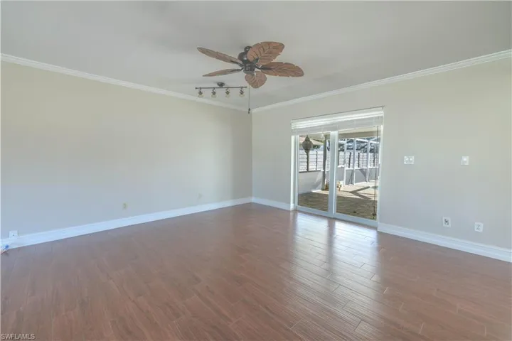 Empty room with wood finished floors, ceiling fan, baseboards, and ornamental molding