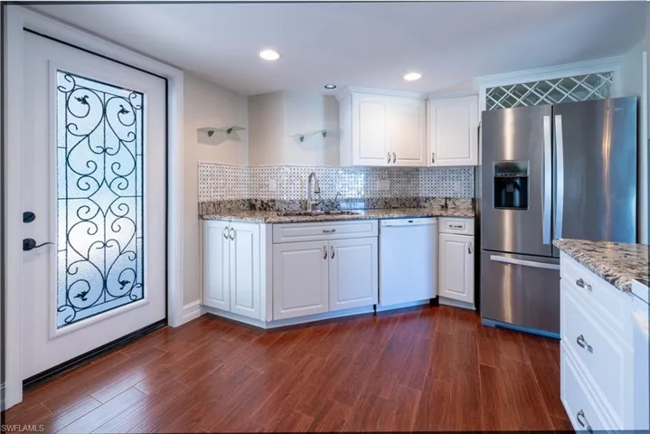 Kitchen featuring stainless steel fridge with ice dispenser, backsplash, white cabinets, white dishwasher, and a sink