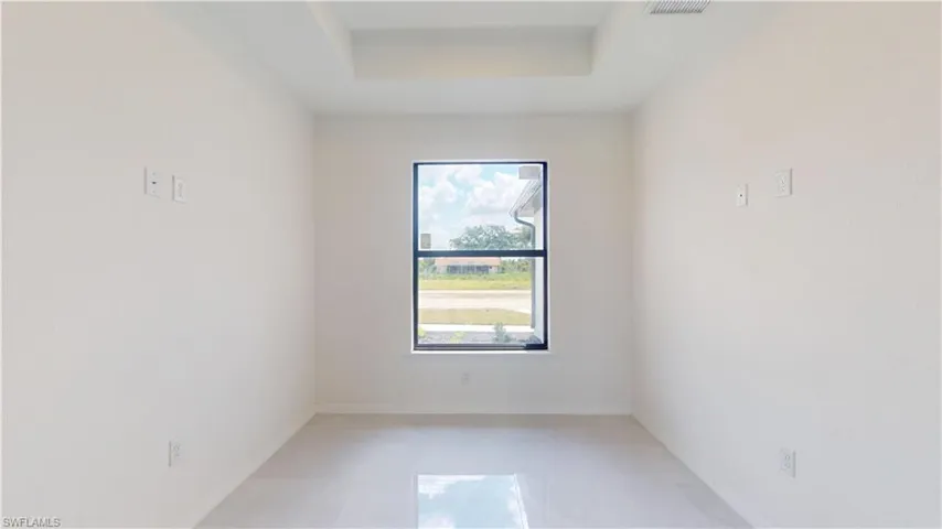 Empty room featuring a tray ceiling and light tile patterned floors