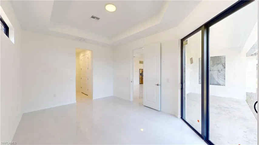 Unfurnished bedroom featuring a raised ceiling, multiple windows, and access to exterior