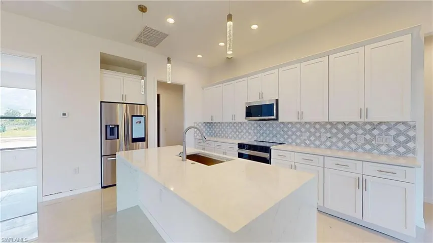 Kitchen with white cabinets, stainless steel appliances, light stone counters, recessed lighting, and backsplash