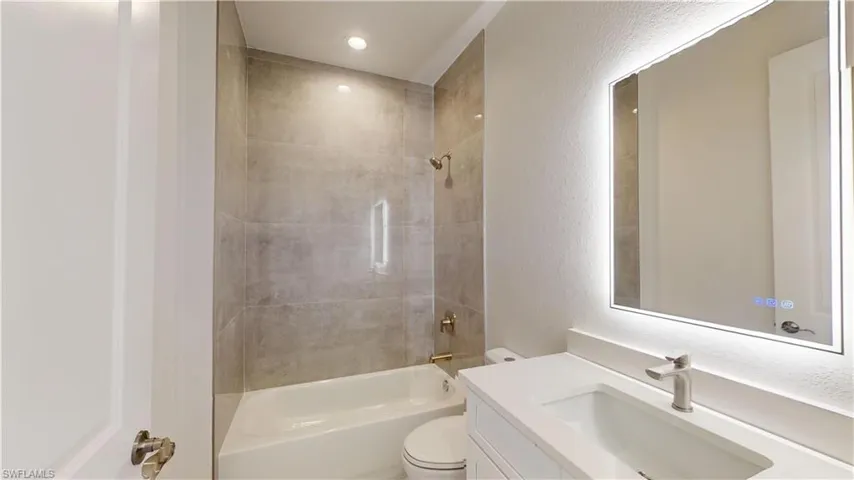 Bathroom featuring a textured wall, shower / washtub combination, and vanity