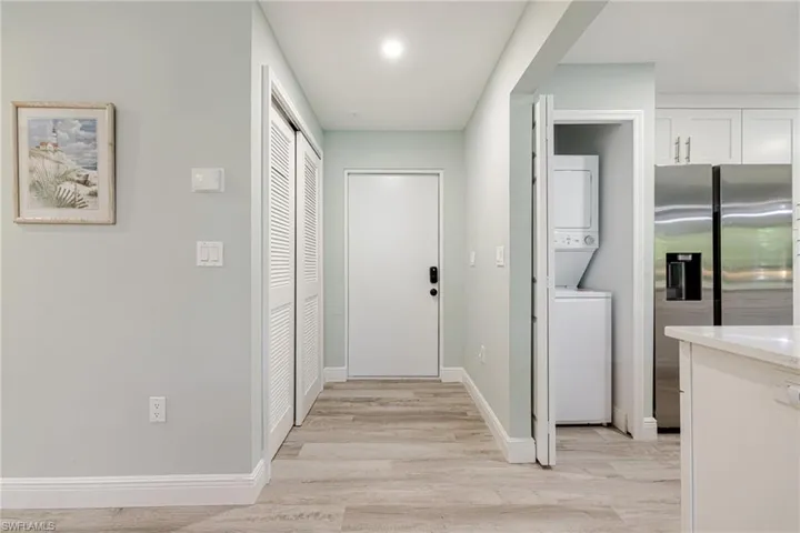 Laundry area featuring stacked washer / dryer and light wood-type flooring