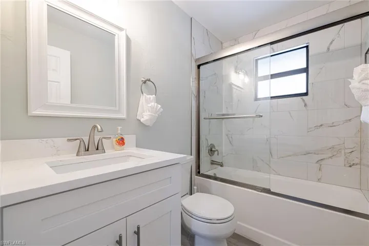 Primary bath featuring shower / bath combination with glass door and vanity