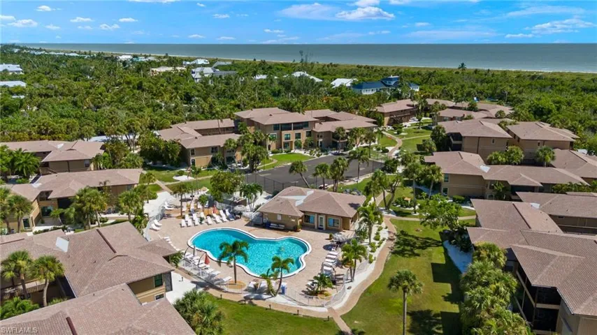 Aerial view of residential area featuring a nearby body of water and a pool