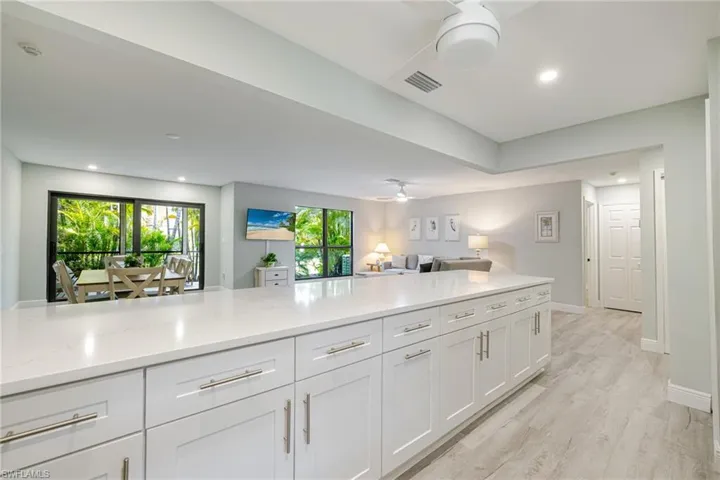 Kitchen featuring white cabinetry, open floor plan, light wood-type flooring, recessed lighting, and light stone countertops