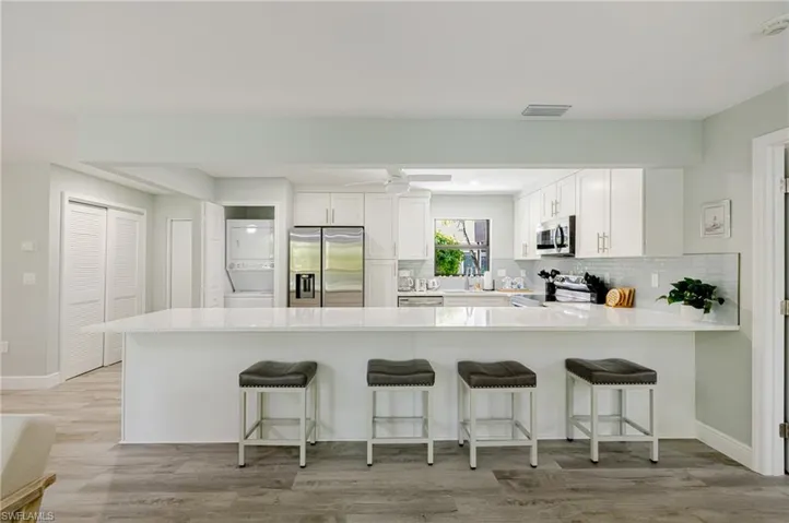 Kitchen featuring a peninsula, stainless steel appliances, white cabinetry, a breakfast bar area, and light wood-style floors