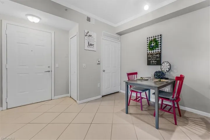 Dining space with crown molding and light tile patterned floors