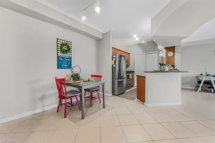 Kitchen with track lighting, appliances with stainless steel finishes, brown cabinetry, a peninsula, and crown molding