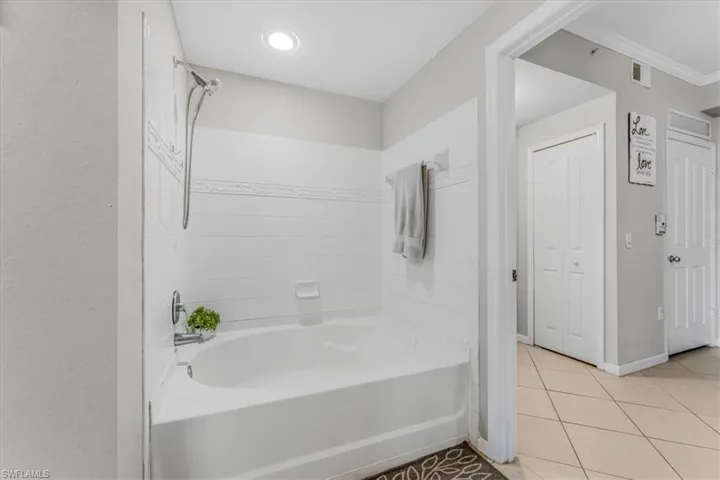 Full bathroom featuring tile patterned flooring, crown molding, and washtub / shower combination