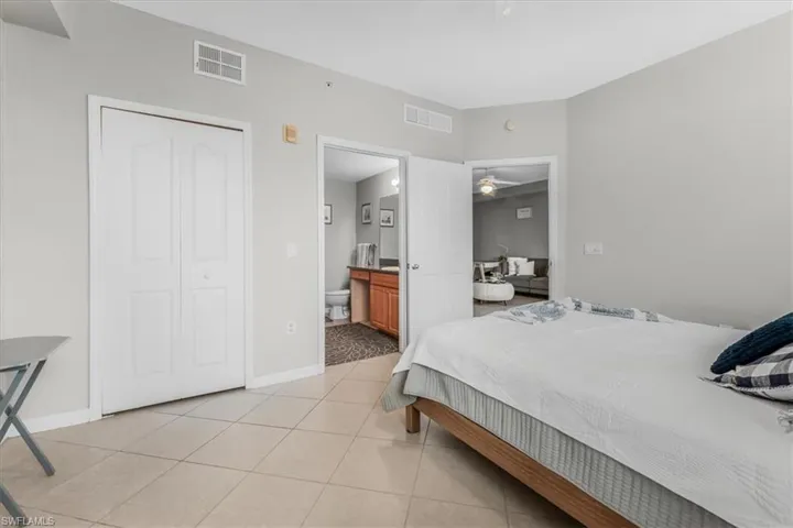 Bedroom with light tile patterned floors, ensuite bath, and a closet