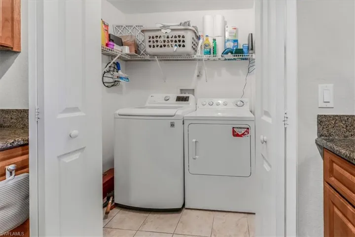 Laundry room with independent washer and dryer and light tile patterned floors
