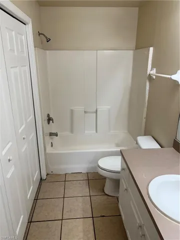 Full bath with  shower combination, vanity, light tile patterned flooring, and a closet