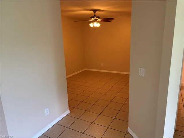 Empty room with light tile patterned flooring and a ceiling fan