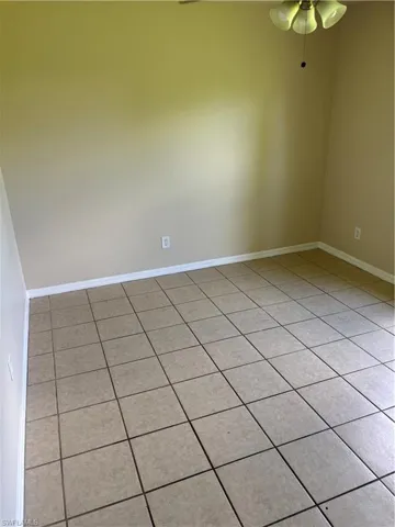 Empty room with light tile patterned flooring and a ceiling fan