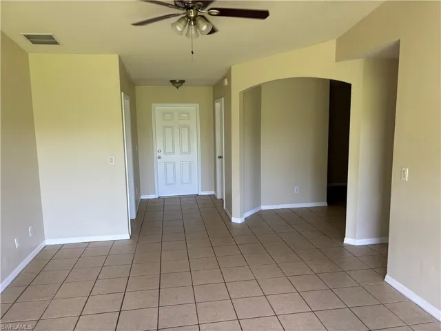 Spare room featuring arched walkways, light tile patterned flooring, and ceiling fan
