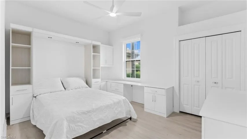 Bedroom with a closet, ceiling fan, built in desk, and light hardwood / wood-style floors