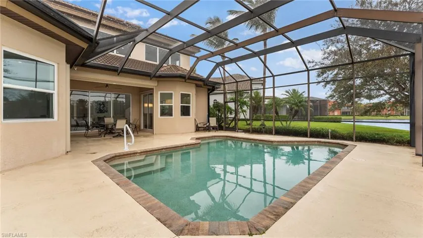 View of pool featuring glass enclosure, a patio area, and ceiling fan