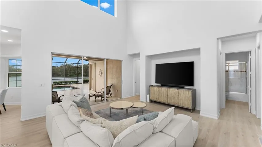 Living room with a towering ceiling and light hardwood / wood-style flooring