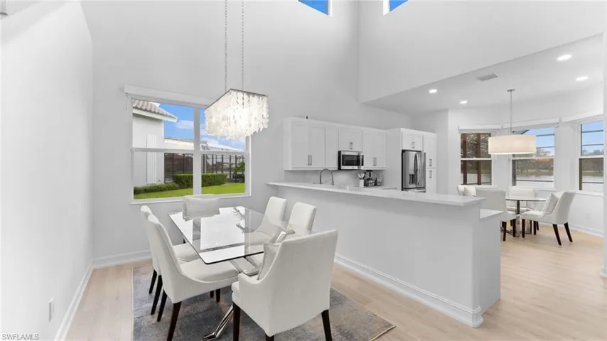 Dining area featuring a towering ceiling, a chandelier, sink, and light hardwood / wood-style flooring