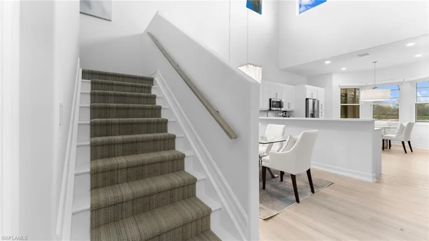 Staircase featuring a towering ceiling and hardwood / wood-style flooring
