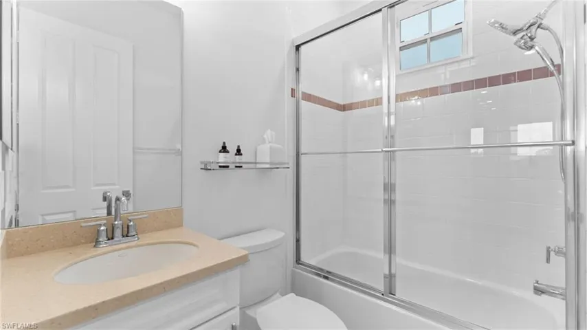 Full bathroom with bath / shower combo with glass door, vanity, and toilet