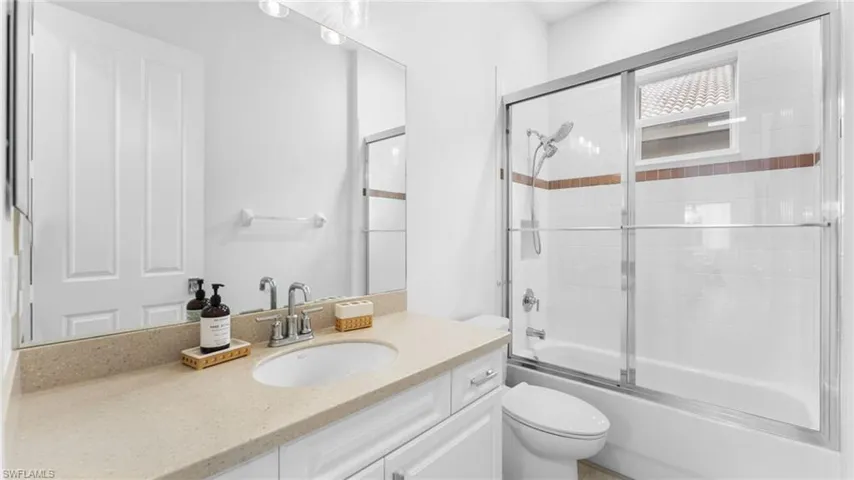 Full bathroom with shower / bath combination with glass door, vanity, and toilet