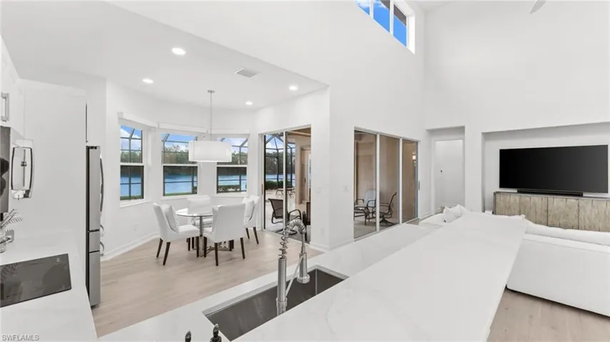 Living room with a towering ceiling, light hardwood / wood-style flooring, and sink