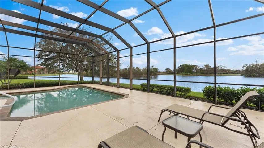 View of swimming pool featuring a water view, glass enclosure, and a patio area