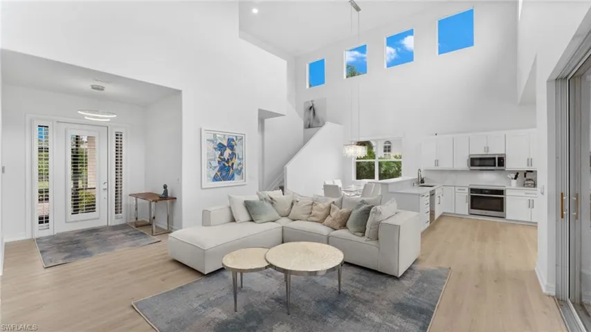 Living room featuring a high ceiling, sink, and light hardwood / wood-style flooring