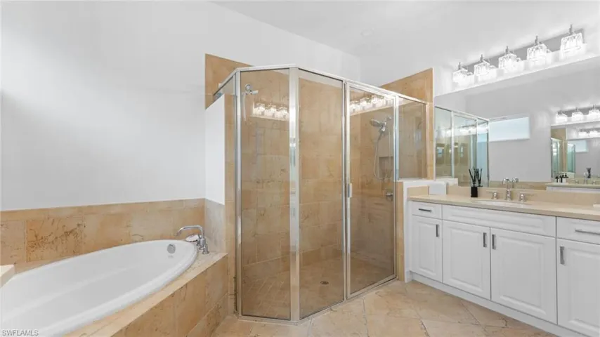 Bathroom featuring tile patterned floors, vanity, and shower with separate bathtub