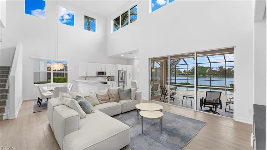 Living room with light wood-type flooring, a water view, and a high ceiling