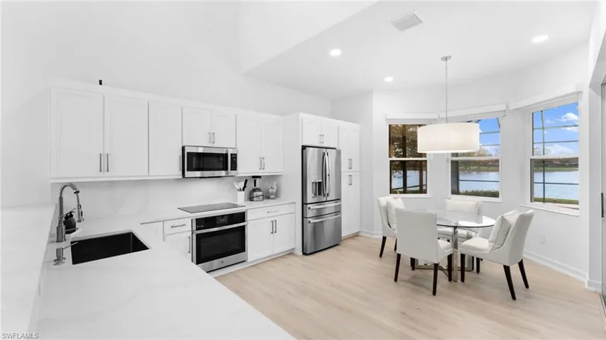 Kitchen with a water view, white cabinets, sink, pendant lighting, and appliances with stainless steel finishes