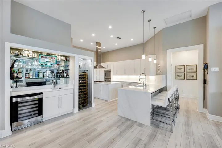 Bar cabinetry matches kitchen with a quartz countertop and wet bar, wine refrigerator and glass wine display.