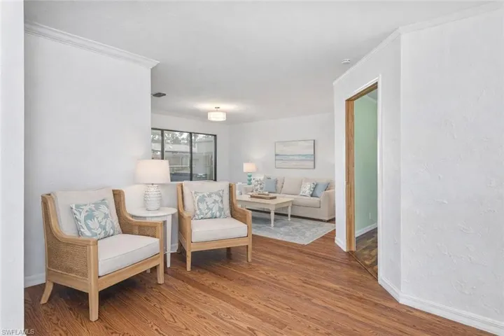 Sitting room featuring ornamental molding, wood finished floors, and a textured wall