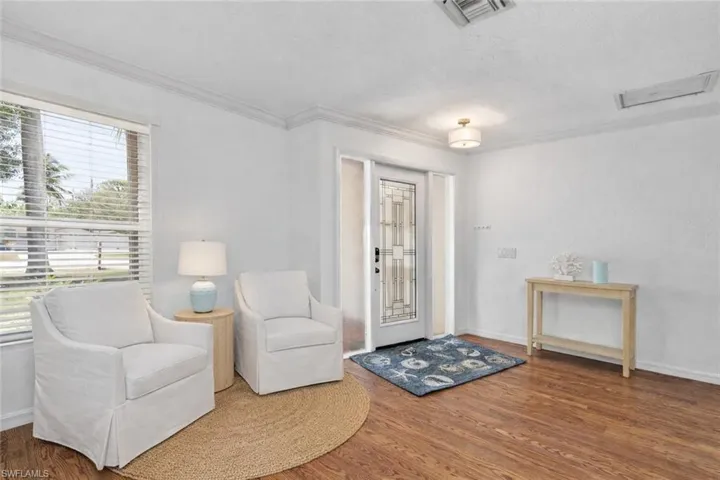 Sitting room with wood finished floors and ornamental molding