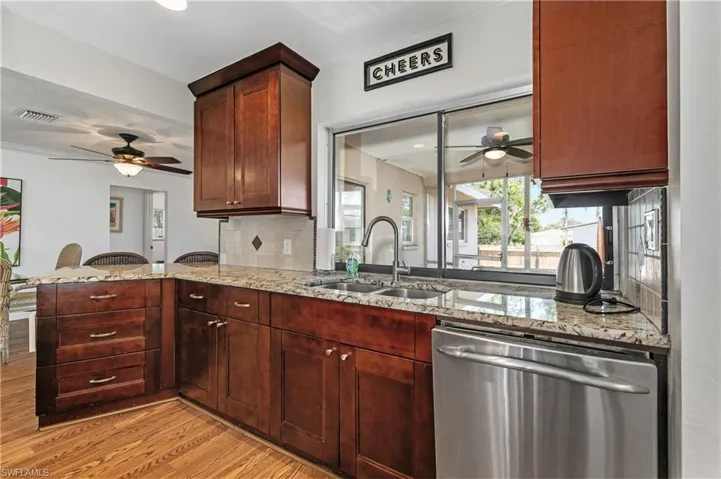 Kitchen with a ceiling fan, light stone counters, stainless steel dishwasher, backsplash, and recessed lighting