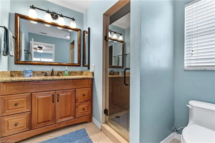 Bathroom featuring vanity, light tile patterned floors, a shower stall, and ceiling fan