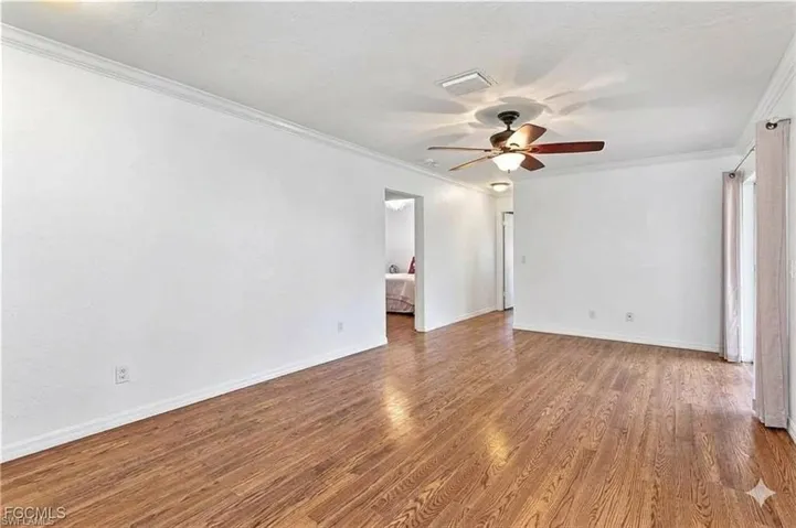Spare room featuring ornamental molding, dark wood-style flooring, and a ceiling fan
