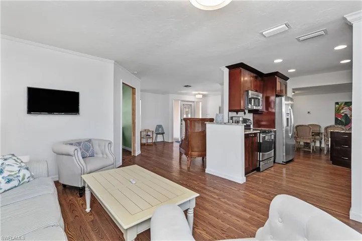 Living area with dark wood-type flooring, a textured ceiling, and recessed lighting
