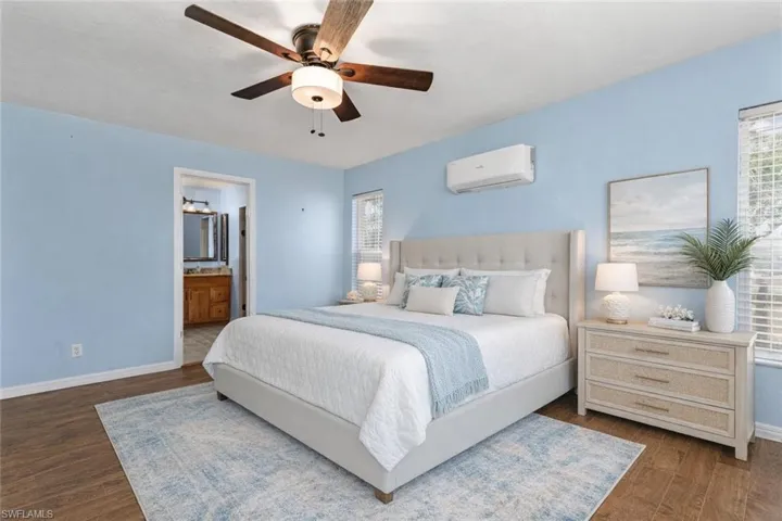 Bedroom with a ceiling fan, ensuite bathroom, and dark wood finished floors