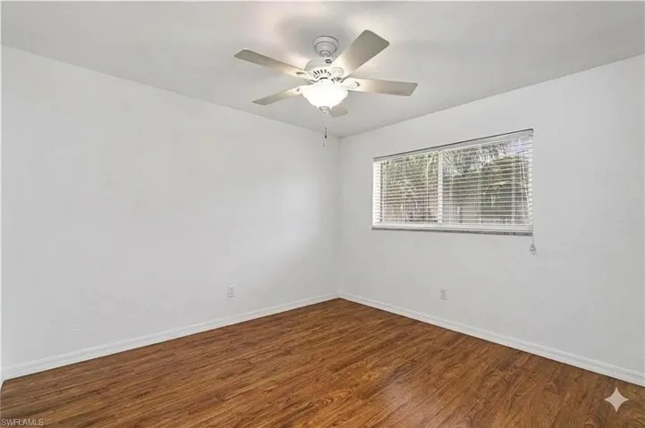 Spare room with dark wood-style floors and a ceiling fan