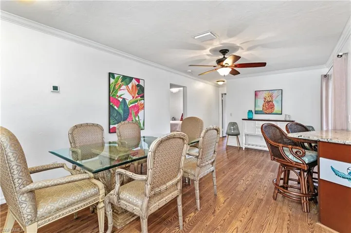 Dining area featuring crown molding, dark wood-type flooring, ceiling fan, and a textured ceiling