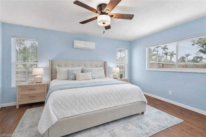 Bedroom featuring multiple windows, ceiling fan, and dark wood-style floors