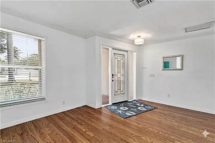 Foyer with dark wood finished floors and ornamental molding