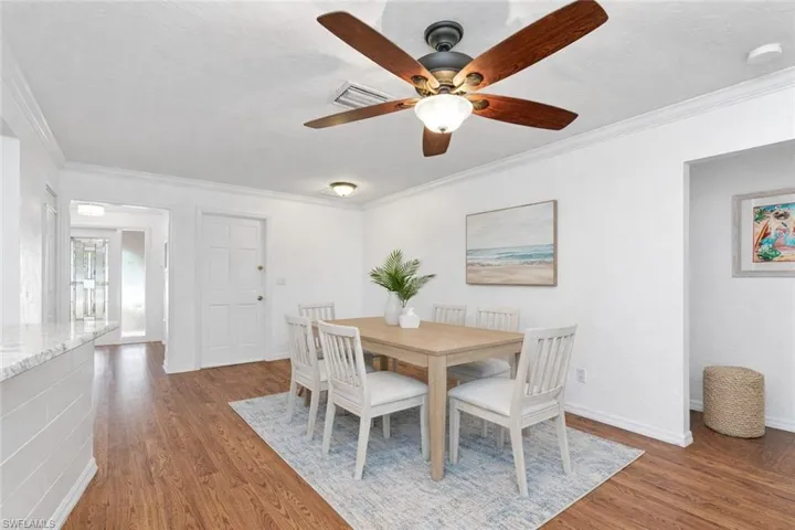 Dining space with crown molding, dark wood-type flooring, and a ceiling fan