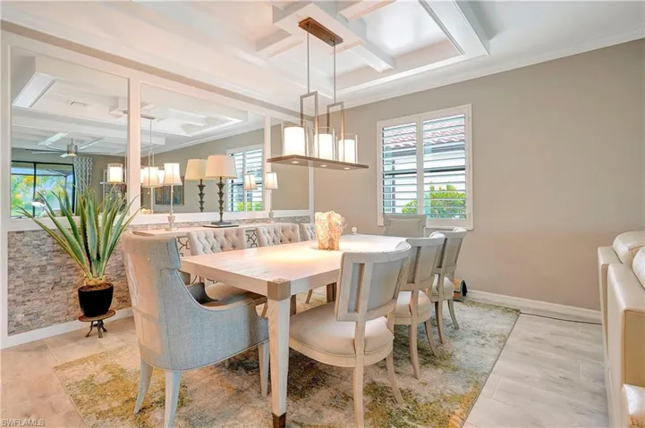 Dining space featuring crown molding, light tile patterned floors, ceiling fan, beamed ceiling, and coffered ceiling