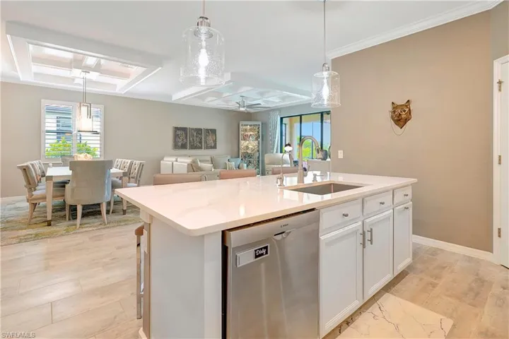 Kitchen with a healthy amount of sunlight, an island with sink, sink, dishwasher, and coffered ceiling