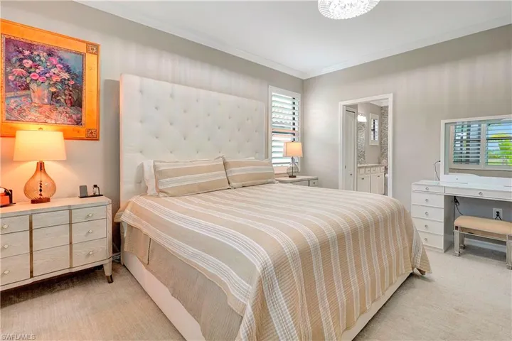 Bedroom with light carpet, connected bathroom, and ornamental molding