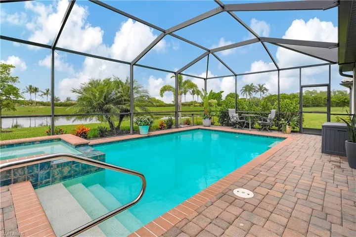 View of swimming pool with an in ground hot tub, a patio, and glass enclosure